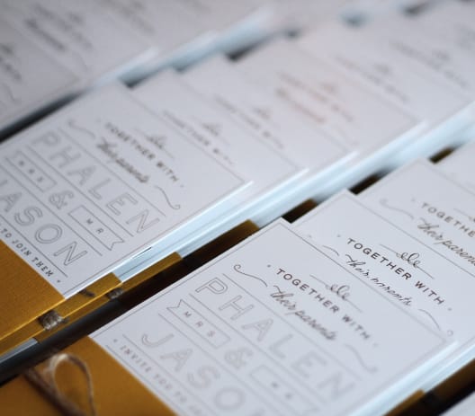 A close up image of many beautifully designed invitations neatly ordered in rows.